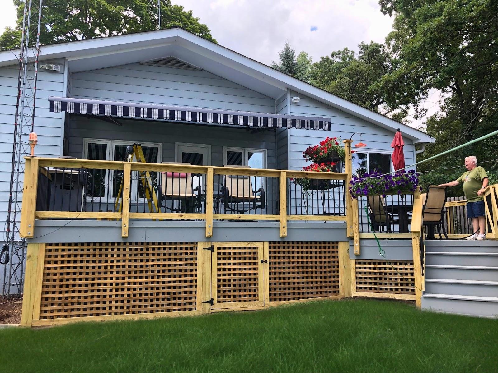 Back of a Lake Zurich home with a custom wood deck featuring lattice skirting, blue stain, and aluminum pickets.